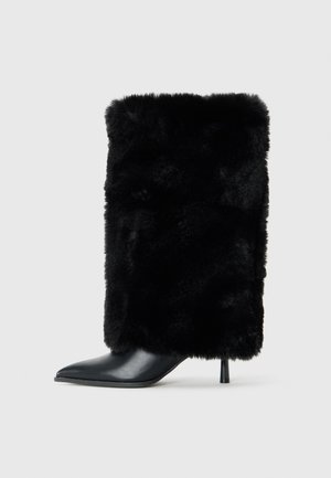 Stivaletto nero con punta a punta e tacco a stiletto, caratterizzato da un'asta in morbido pelo sintetico nero. Dettaglio in pelle liscia sulla punta.