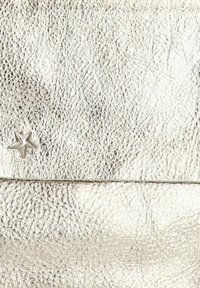 Hopea metallinen tekstuuri nahkapinta, jossa on pieni kiiltävä tähti-muotoinen metallikoriste sauman lähellä.