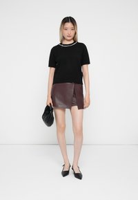 Black short-sleeve sweater with pearl detailing at the neckline, paired with a burgundy leather mini skirt and black pointed-toe shoes.