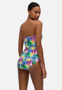Bañador de una pieza sin tirantes con un estampado de hojas tropicales en colores vibrantes. Confeccionado en una tela suave y elástica, presenta un diseño ajustado.