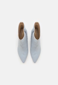 Par de botines de ante azul claro con cremalleras laterales, puntera afilada y forro interior color marrón claro, vistos desde arriba sobre fondo blanco.