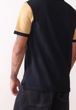 Navy and beige short-sleeve polo shirt with a contrasting collar, featuring a smooth texture and side slits at the hem.