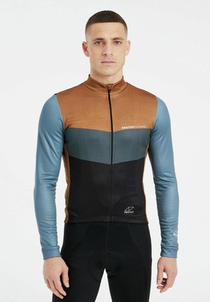 Man draagt een bruin, zwart en blauw lang mouwen wielertrui met het logo "Protest Cycling", staand tegen een witte achtergrond.