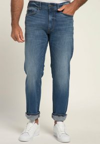 Jeans de mezclilla azul claro con un corte relajado, puños enrollados, un ligero desgastado, diseño de cinco bolsillos y cierre de botones, combinados con zapatillas blancas.