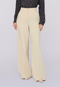 Creme kleurige wijde broek gemaakt van zachte stof met een gladde textuur, met een hoge taille en een minimalistisch ontwerp.