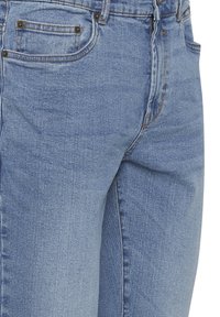 Gai zila džinsu auduma bikses ar pieguļošu griezumu, ar priekšējo rāvējslēdzēju, pieciem kabatām un kontrastējošu šuvju izšuvumu.