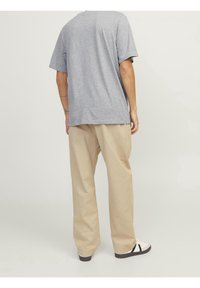 Camiseta de algodón gris combinada con pantalones de pierna ancha beige. Los pantalones tienen un corte relajado, mientras que la camiseta tiene un escote redondo y mangas cortas.