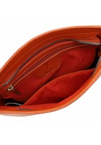 Orange leather clutch bag interior, featuring a zippered pocket and two open compartments, lined with red fabric. Smooth texture and metal hardware.