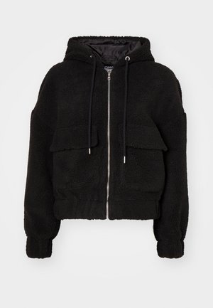 Black hooded bomber jacket made of plush fabric, featuring a zip front, two front pockets with flaps, and elastic cuffs.