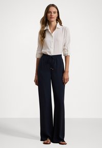 White linen button-up shirt with rolled sleeves, paired with navy wide-leg pants featuring an elastic waistband and drawstring closure.