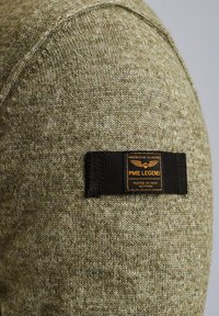 Olivengrøn strikket sweater med en struktureret overflade. Har et sort stofmærke med orange tekst, der står "PME LEGEND" samt andre detaljer.