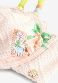 Borsa imbottita in morbido tessuto pesca con ricami floreali verdi e blu, arricchita da una chiusura decorativa dorata e da manici colorati con perline.