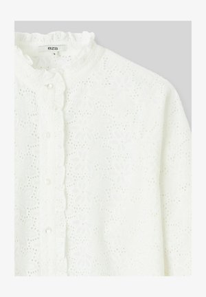 Blouse blanche en tissu texturé avec broderie florale, col à volants et fermetures à boutons sur le devant.