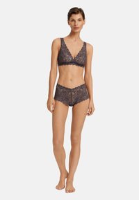 Černá krajková braletka a odpovídající šortky ve tmavě šedé barvě. Mezi hlavní rysy patří vlnité okraje, květinové vzory a měkký, strukturovaný povrch.
