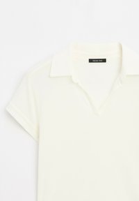 Kratší rukávy, světle žlutá polokošile s výstřihem do V a límečkem. Má jemnou texturu a černou etiketu na výstřihu.