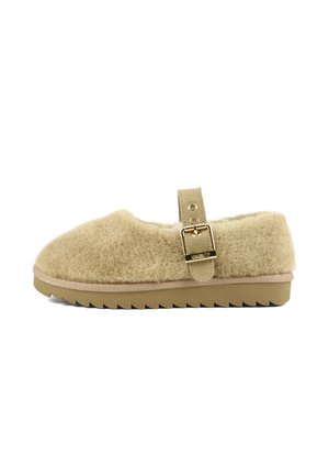 Chaussure beige duveteuse sans lacets avec une semelle en caoutchouc rainurée et une bride réglable avec boucle dorée sur le dessus.