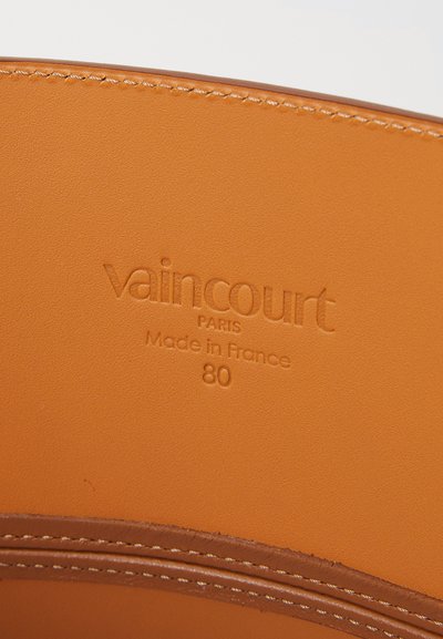 Intérieur en cuir orange avec logo en relief "vaincourt," emplacement "Paris," et texte "Fabriqué en France" avec une texture lisse.