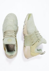 Světlounce zelené sportovní boty s texturou z mřížky, elastickými tkaničkami a gumovou podrážkou. Obsahují značení Nike a polstrovanou patu pro pohodlí.