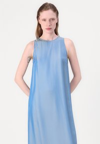 Blue sleeveless dress in lightweight fabric with a smooth texture; features a round neckline and a fluid, slightly a-line silhouette.