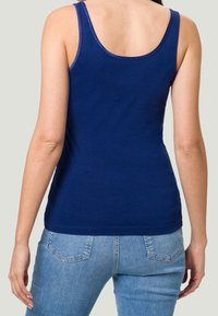 Débardeur sans manches bleu marine en tissu doux ; présente un col rond et des bretelles étroites, associé à un jean en denim bleu clair.