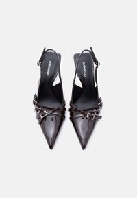 Escarpins slingbacks noirs brillants à bout pointu avec double boucle, semelles intérieures de marque et talon carré bas sur fond blanc.