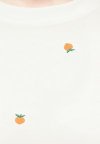 Λευκό ύφασμα με δύο μικρά κεντημένα πορτοκαλί ροδάκινα με πράσινα φύλλα τοποθετημένα με απόσταση.