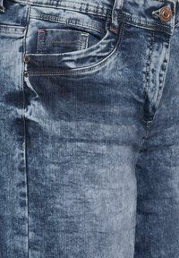 Verbleekte blauwe denim jeans met een vijf-pocket ontwerp, kopertint knoop en duidelijke textuurvariaties in de stof.