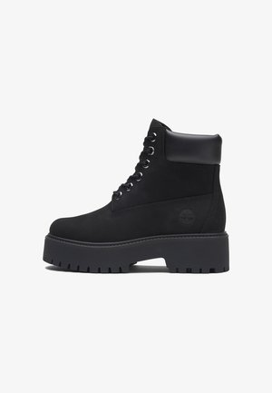 Bottine noire à lacets avec semelle épaisse à crampons et col rembourré, logo latéral embossé sur dessus en cuir mat.