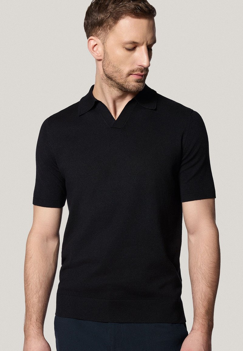 Czarny polo z krótkim rękawem, z dekoltem w kształcie litery V i płaskim kołnierzykiem, o gładkiej dzianinowej fakturze i ściągaczu u dołu.