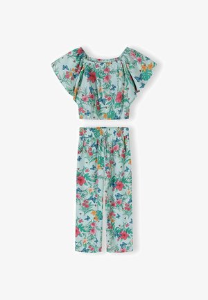 Ensemble deux pièces bleu clair à motifs floraux avec top court à volants et épaules dénudées, et pantalon à jambes larges orné de fleurs colorées et de feuilles vertes.