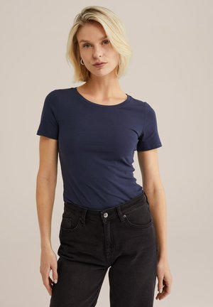 Marinblå figursydd t-shirt med rund halsringning och korta ärmar, parat med svarta högmidjade jeans. Mjuk, slät tygtextur.