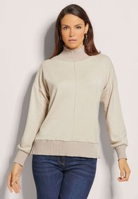 Beige geribbelde gebreide trui met een hoge hals, drop shoulders en geribbelde manchetten en zoom. Voorzien van een gladde textuur, een ontspannen pasvorm en minimale naaddetails.