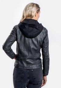 Zwarte leren jas met een gestructureerde afwerking, voorzien van een zwarte stoffen capuchon, aansluitend ontwerp en zichtbare stiksels.