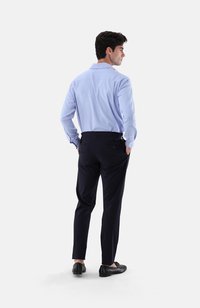 Hellblaues langärmliges Hemd mit yoke hinten, kombiniert mit dunklen marineblauen Slim-Fit-Hosen. Schwarze Schuhe runden das Outfit ab.