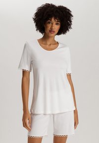 Top blanco de manga corta con cuello redondo y borde festoneado en las mangas, combinado con pantalones cortos blancos a juego que presentan un detalle de borde similar.