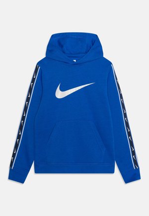 Sudadera azul con capucha hecha de algodón, con un gran logo blanco de Nike en el frente, bolsillo delantero y rayas negras y blancas con patrón en las mangas.