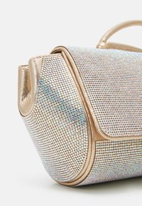 Sac à main métallique orné de strass irisés, présentant une forme arrondie élégante et une fermeture à rabat discrète. Texture lisse avec des accents dorés.