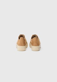 Sneakers in pelle marrone chiaro con superficie testurizzata, presentano una suola in gomma di colore chiaro, forma arrotondata e dettagli di cucitura delicati.
