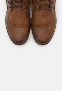 Chaussures en cuir marron avec une surface texturée, embout arrondi et lacets sombres contrastants. Présente un design de bout lisse et une semelle durable.