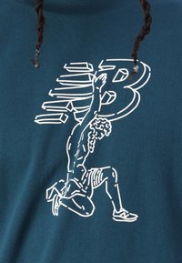 Teal bomulds T-shirt med et hvidt grafik af en knælende figur med krøllet hår, prydet med et stiliseret "B" logo integreret i designet.