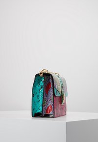 Borsa multicolore con stampa effetto pelle di serpente in tonalità turchese, rosa e viola, con tracolla a catena dorata e forma rettangolare.