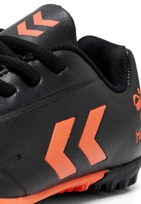 Scarpe sportive nere con dettagli arancioni, caratterizzate da una tomaia in pelle testurizzata, lacci piatti e una suola in gomma con motivo per una migliore trazione.