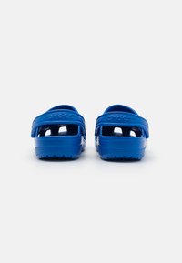 Blue rubber clogs with an open back, vented sides, and a textured sole. Features the embossed "crocs" logo on the straps.