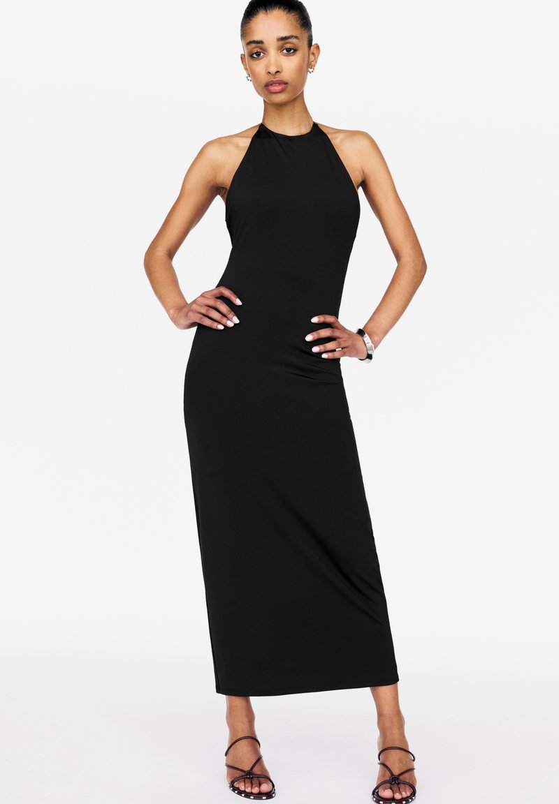 Robe maxi noire à col halter, réalisée en tissu lisse, avec une silhouette ajustée et une coupe jusqu'au sol, agrémentée d'accents minimalistes.