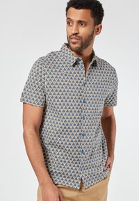 Korte mouwen overhemd met knopen in een blauw en crème geometrisch patroon, voorzien van blauwe knopen en een kraag.