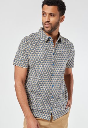 Camicia a maniche corte con bottoni, in un motivo geometrico blu e crema, con bottoni blu e collo a camicia.