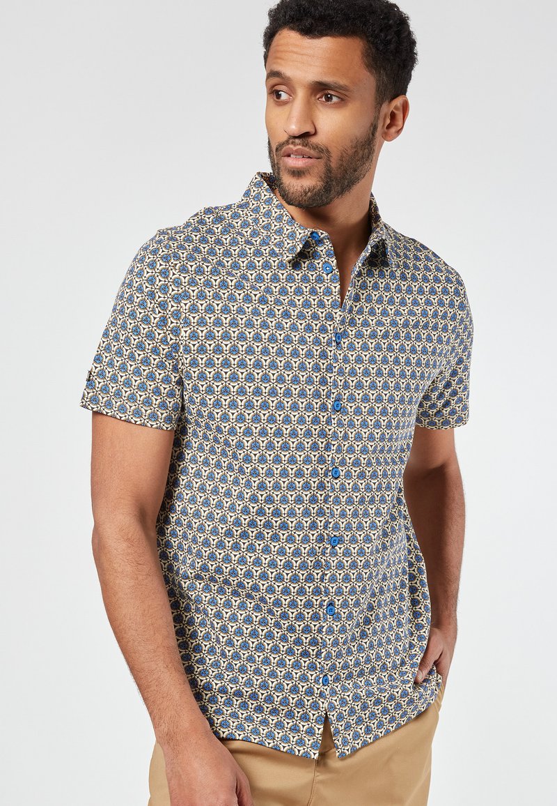 Korte mouwen overhemd met knopen in een blauw en crème geometrisch patroon, voorzien van blauwe knopen en een kraag.