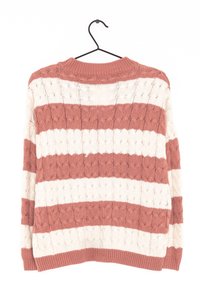 Pull en tricot avec des rayures horizontales en rose clair et crème. Présente un motif texturé et un col à côtes. Accroché à un crochet noir.