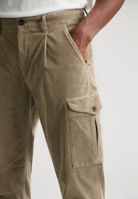 Karakul cargo-bukser i khaki med en avslappet passform, med frontlommer, en sidelomme og subtil tekstur.