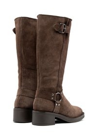 Botas altas de ante marrón, con tacón plano, que presentan un elegante detalle de hebilla y tira. La parte superior tiene una textura suave.